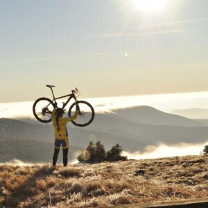 Women lifting a bike on a sunny mountain symbolising increasing the value of your company