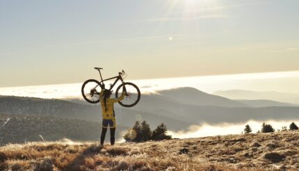 Women lifting a bike on a sunny mountain symbolising increasing the value of your company
